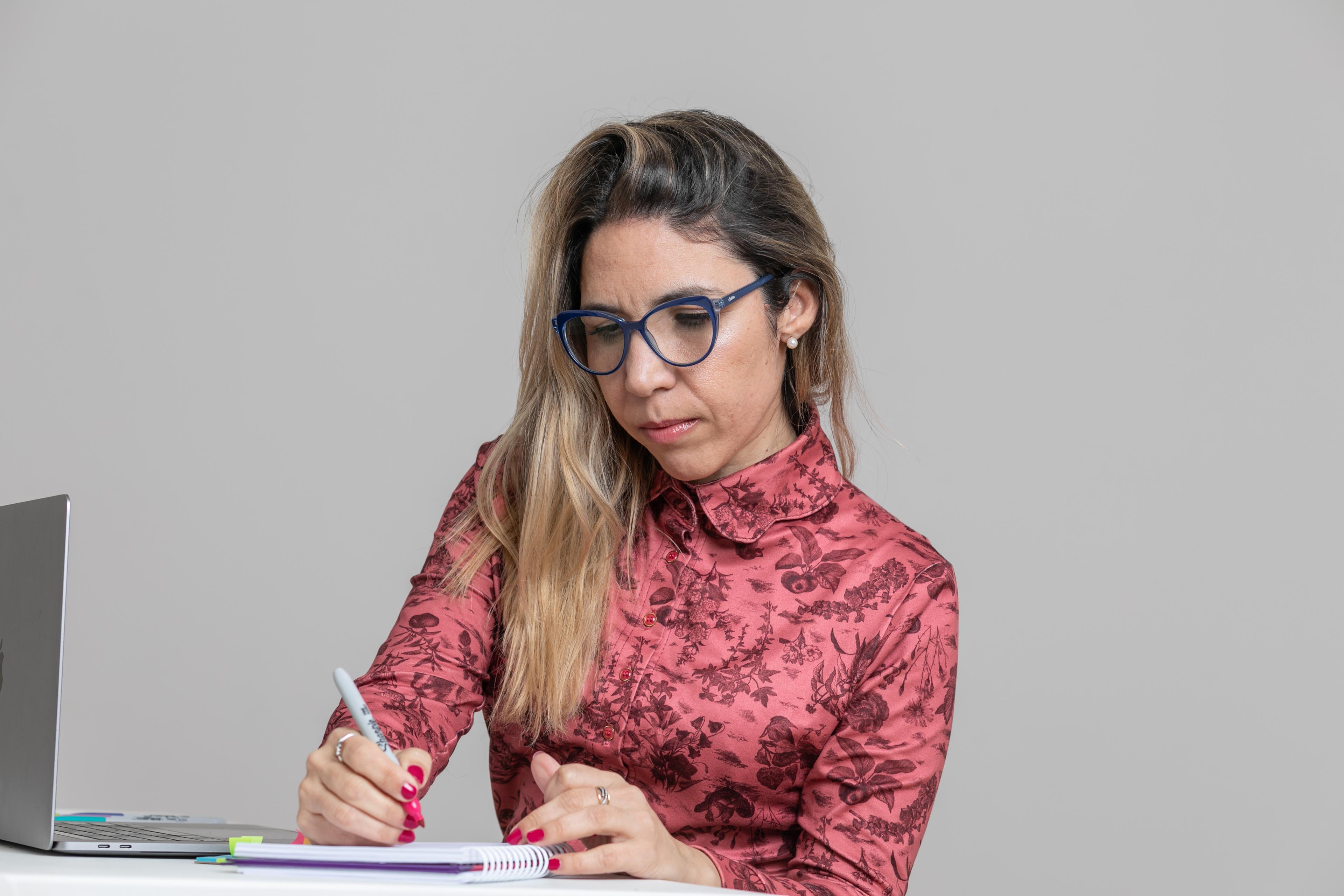 Melisa escribe en un cuaderno junto a su computadora
